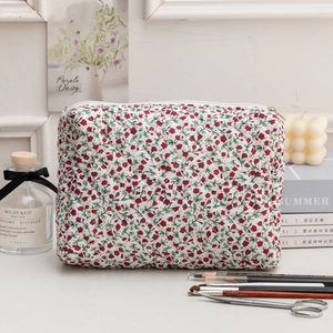 Detail of red floral quilted cosmetic bag with rhombus texture and white zipper