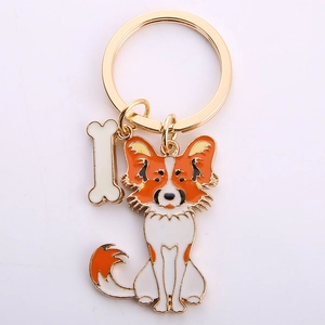 Macro detail of metal butterfly dog keychain with orange enamel and bone charm
