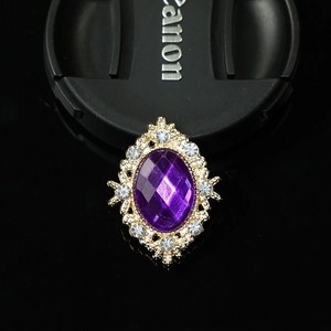 Macro detail of oval purple gemstone brooch with gold filigree and sparkling rhinestones
