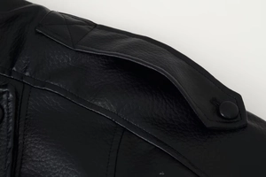 Close-up of black faux leather jacket shoulder featuring epaulet detail and matte button