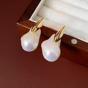 Close-up of irregular Baroque pearl earrings with gold plating on a wooden jewelry box