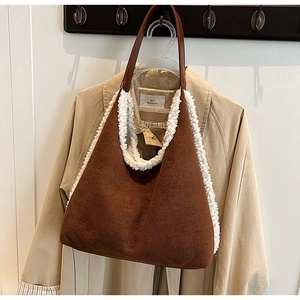 Close-up of brown faux suede tote bag with white faux shearling trim on wooden hanger