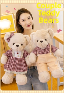 Detail of plush teddy bear couple in plaid outfits held by a model in a warm setting