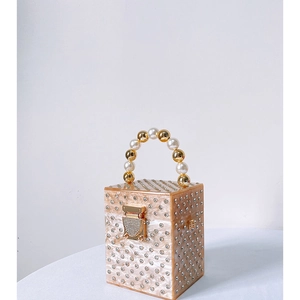 Macro detail of acrylic evening box bag with rhinestone studs and pearl bead handle