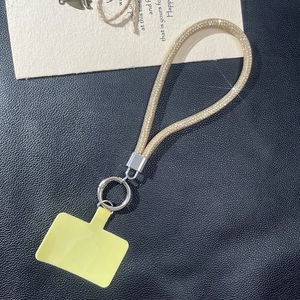 Golden rhinestone phone wrist strap with silver metal clasp and yellow connector pad
