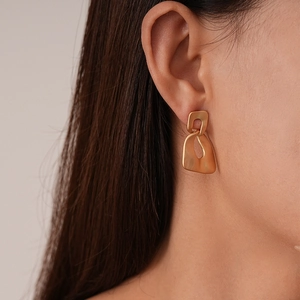 Detailed close-up of matte gold irregular geometric earrings with minimalist artistic design