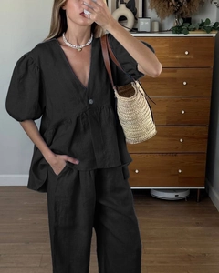 Detail of black linen-style set showing V-neck puff sleeve top and wide-leg pants texture