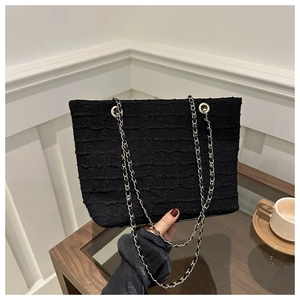 Close-up of black ruched tote bag with elegant gold and black interwoven chain strap