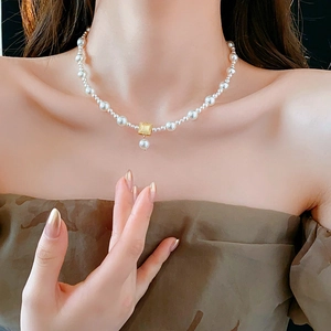 Detail of 18k gold plated pearl necklace with square pendant on model's neckline