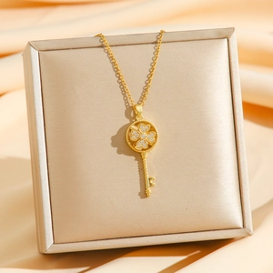 Golden rotating clover key pendant necklace with zircon inlays on a gift box