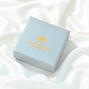 Detailed view of light blue square jewelry gift box on white silk with golden text