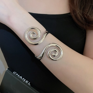 Detail view of a silver spiral upper arm cuff with ancient Greek style swirl design
