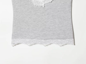 Detailansicht der weißen floralen Spitzenbordüre an einem hellgrauen Strickoberteil