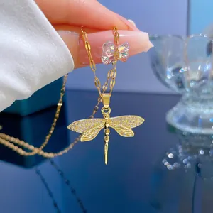 Detail of gold dragonfly necklace with crystal wings and a colorful bear charm accent