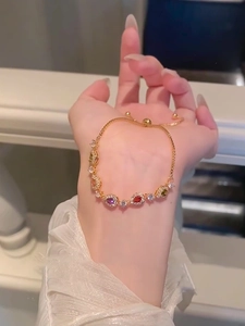 Detail of elegant gold bracelet featuring colorful teardrop-shaped zircons and sliding clasp