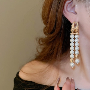 Detail of layered pearl tassel earrings with embossed gold rings on a model