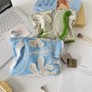 Detail of vintage cotton-linen cosmetic pouches with 3D floral embroidery and fringe