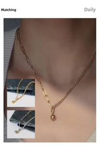 Detail of asymmetric gold and silver mixed chain necklace with polished sphere pendant