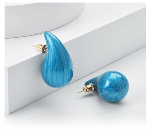 Macro detail of chunky blue teardrop earrings with elegant golden studs and flowing texture
