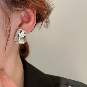 Close-up of irregular geometric silver stud earring with liquid metal mirror finish