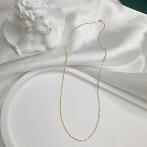 Detail of elegant gold-plated S925 sterling silver chain necklace on white satin with angel