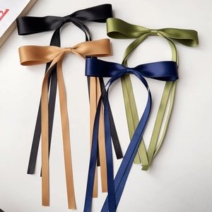 Flat lay of four colorful satin bow hair clips with long ribbons in multiple colors