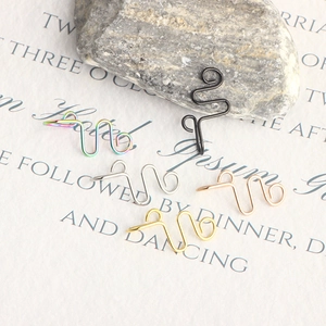 Macro shot of five-color wave-shaped fake nose rings in gold, silver, and black finish