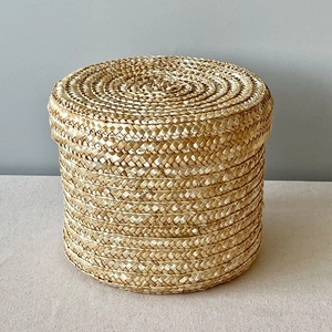 Macro view of a cylindrical handmade woven straw storage box with lid in natural finish