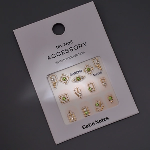 Macro de bijoux d'ongles géométriques dorés avec strass verts et blancs étincelants
