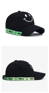 Detail of black baseball cap with white embroidered smile and neon green logo strap