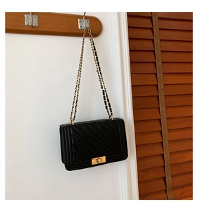 Detail of black V-quilted faux leather crossbody bag with vintage gold chain and turn-lock