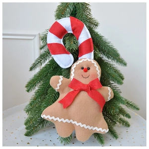 Detail of plush gingerbread man ornament with candy cane hook hanging on Christmas tree