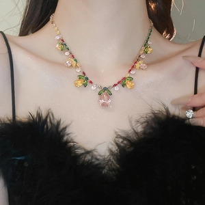 Macro detail of a colorful teardrop gemstone necklace on a model with black feathers