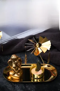 Detail of golden spinning windmill candle holder with angel statue on a tray