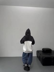 Women's color-block hooded sweatshirt and wide-leg jeans in a minimalist studio setting
