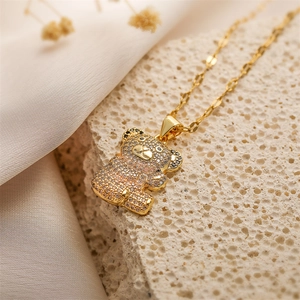 Close-up of a gold bear pendant with micro-pave crystals on a textured beige stone