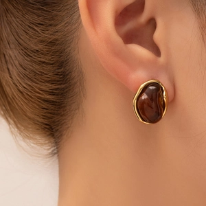 Detail of vintage amber stud earring with irregular gold textured metal edge on ear