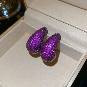 Macro shot of silver teardrop earrings with purple pave-set zircons in jewelry box