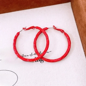 Detailed macro view of large red hoop earrings with unique hammered textured surface