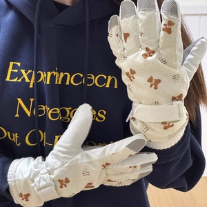 Close-up of white ski gloves with brown bear design and anti-slip fingertips detail