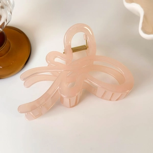 Close-up of translucent pink jelly bow hair claw with sturdy golden metal spring