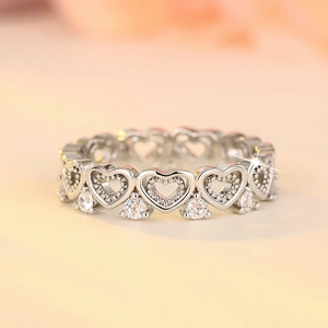 Close-up of silver hollow heart-shaped ring with small cubic zirconia and bead edges