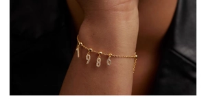 Detail of s925 silver gold necklace with 1986 cubic zirconia number charms on a dark background