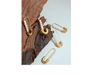 Detail of 18K gold-plated paperclip earring featuring five lustrous pearls on a wooden base