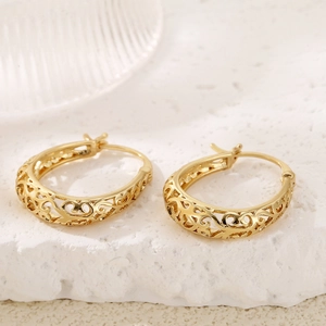 Close-up of golden hoop earrings featuring intricate vintage hollow floral filigree patterns