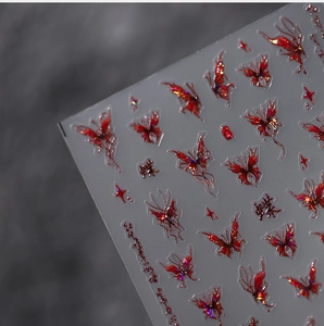 Macro view of metallic red butterfly nail decals with 3D embossed laser effect textures
