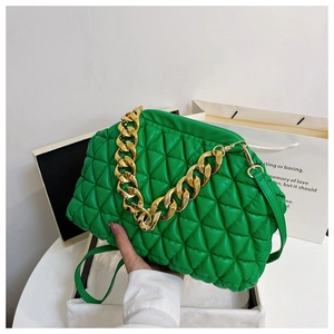 Detail of green quilted bag with large gold chain strap and leather shoulder strap