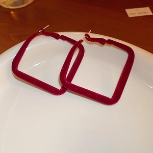Detail view of square wine red velvet earrings on white ceramic plate with silver posts