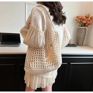 Model view of beige hollow knit tote bag with tassel details for a casual beach look