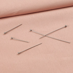 Five 0.6mm stainless steel round head pins for DIY jewelry making on pink fabric